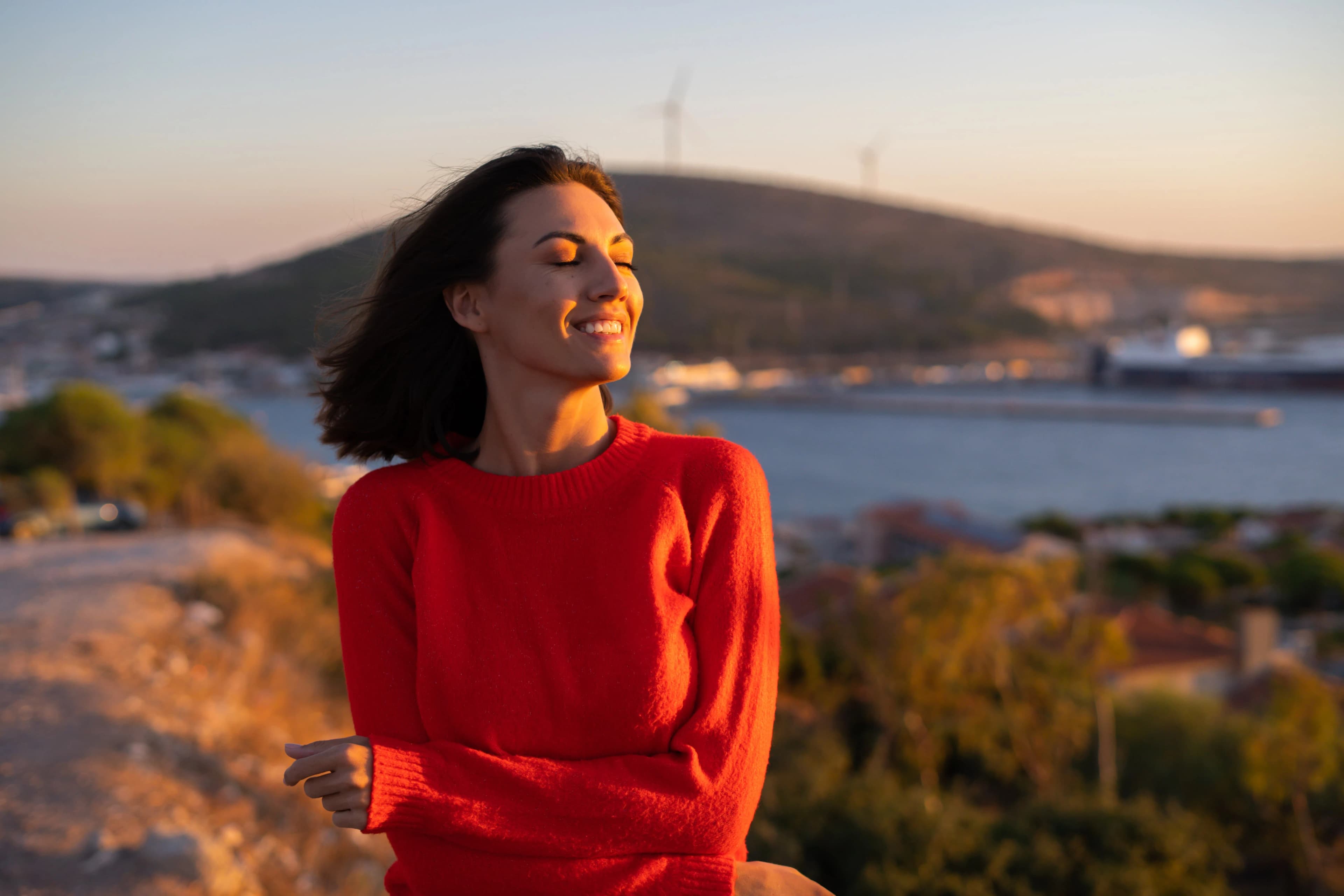 Peaceful woman standing in nature with eyes closed, symbolizing calm and emotional healing